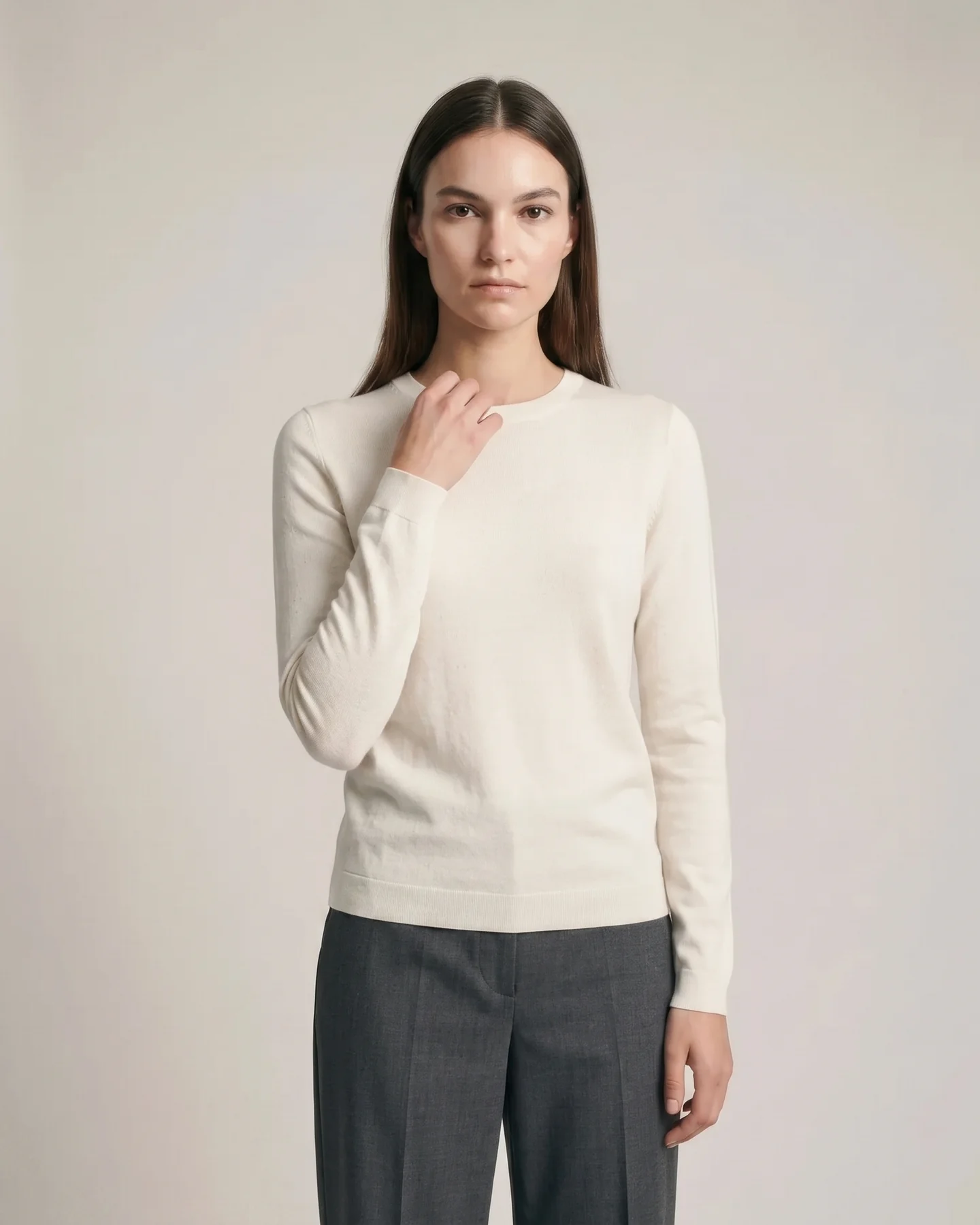 One hand lifted to the collar, the knit gathering at the wrist