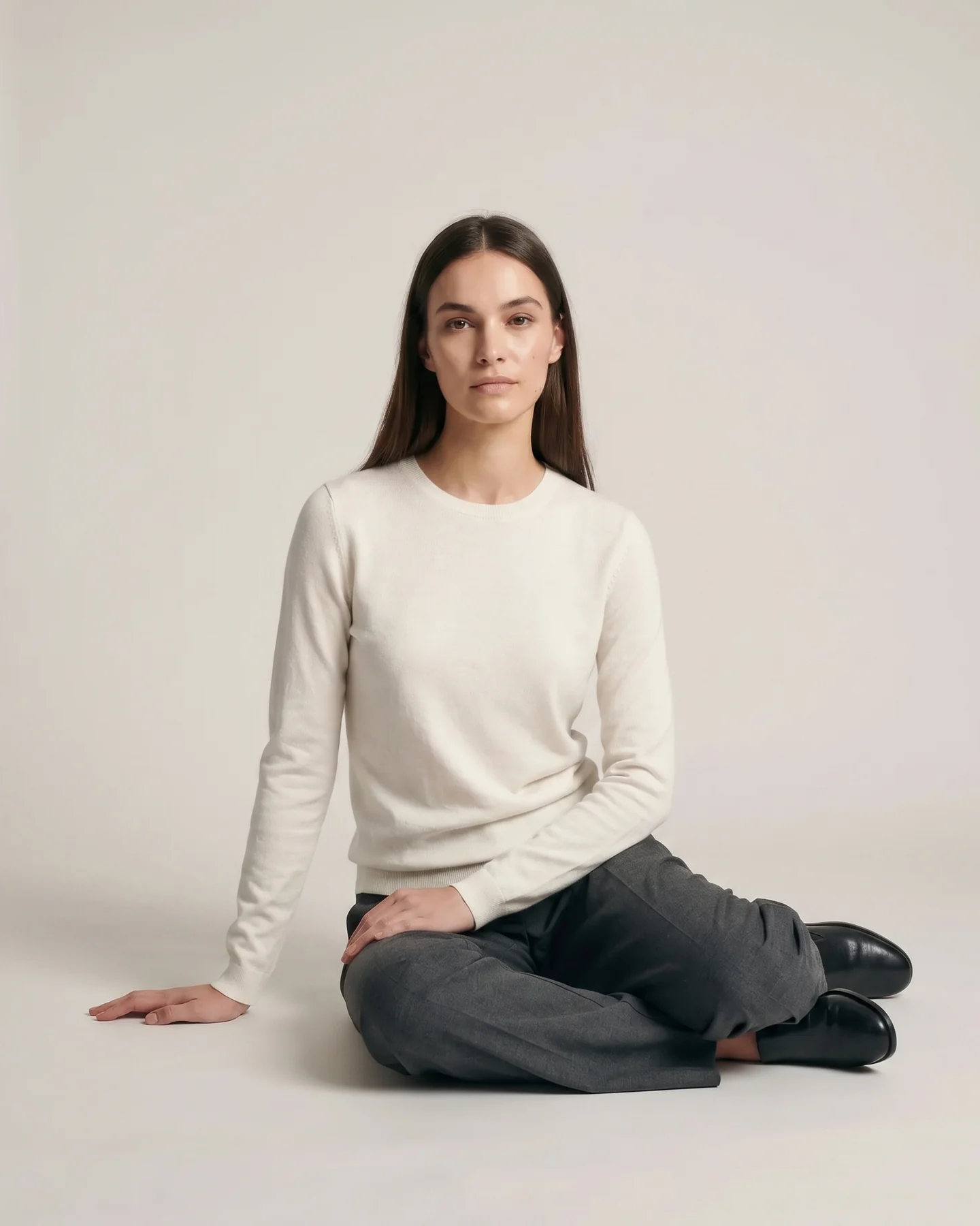 Seated on the floor, the trouser pooling, the knit slack at the arm